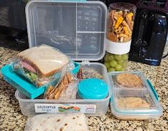 lunch boxes with sandwiches, crackers and grapes