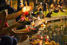 many people are lighting candles on the water