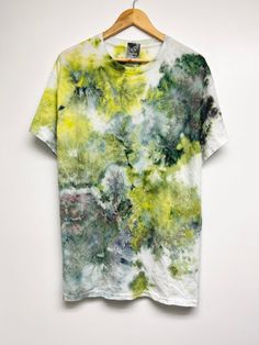 a t - shirt hanging on a hanger with green and yellow paint all over it