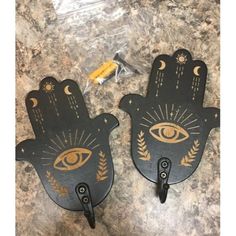 two black and gold hand shaped wall hooks with an eye on the front, one in the middle