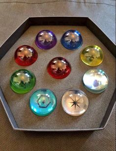 seven glass knobs in a hexagonal box on a table with a white cloth