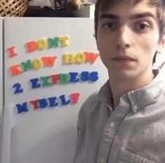 a young man standing in front of a refrigerator with magnets on it's side