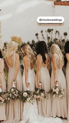 a group of women standing next to each other in long dresses and holding bouquets