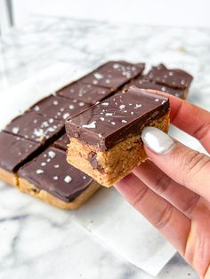 a hand holding up a chocolate bar with white sprinkles on it's side