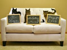 two cats sitting on top of a couch with chalkboards in front of their backs