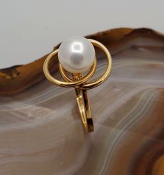 ES2056 Vintage pearl 14k gold ring. 14k yellow gold ring with interlocking circles design set with genuine 8mm white pearl. Hallmark: 14k. Height: 11.8mm. Diameter of circles: 15mmx12mm. Ring size: 6, can be resized, please inquire. This is very fun and playful ring. Modern Round Pearl Ring In Yellow Gold, Modern 14k Gold Pearl Open Ring, Modern 14k Yellow Gold Pearl Ring, Gold Ring With Pearl, Ring With Pearl, Circles Design, Vintage Pearl, Circle Ring, Vintage Pearls