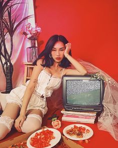 a woman sitting on the floor in front of an old tv with food around her