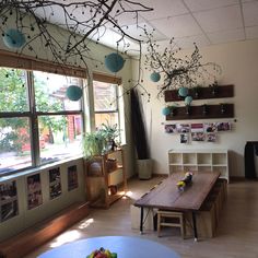 a living room filled with furniture next to a window covered in lots of plants and hanging decorations