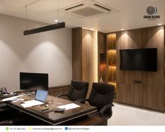 an office with two leather chairs and a large desk in front of a flat screen tv