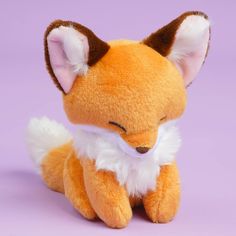 a small stuffed fox sitting on top of a purple surface