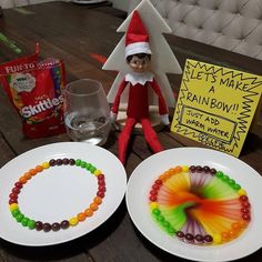 an elf is sitting next to two plates with candy on them