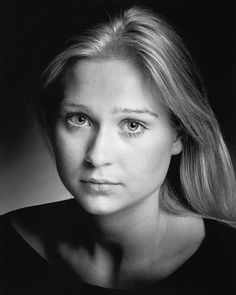 a black and white photo of a woman's face with long blonde hair, looking directly into the camera