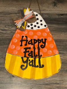 a happy fall y'all sign hanging on a wooden wall with polka dotes