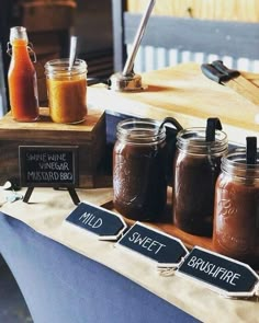 there are many different types of sauces on the table and in mason jars with chalkboard signs