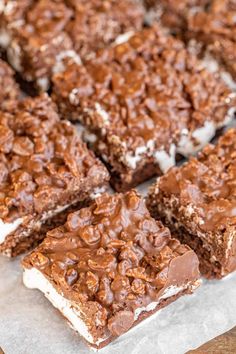 chocolate dessert bars with marshmallows on top sitting on wax paper next to each other