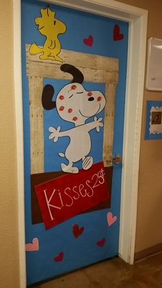 a door decorated with a snoopy dog holding a sign that says kiss me on it