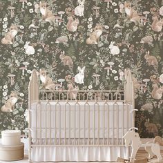 a baby crib in front of a wallpaper with animals and flowers on it