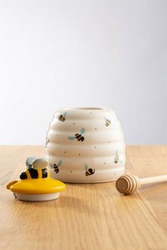 a beehive shaped container with a wooden honey dipper next to it on a table