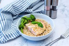 a white bowl filled with rice and broccoli next to a salt shaker