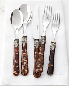 four forks, two spoons and one knife on a napkin with an animal print design