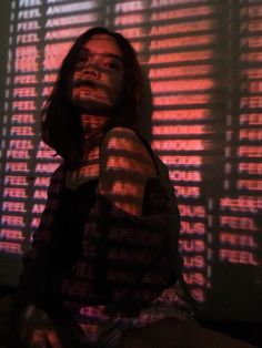 a woman sitting in front of a window with blinds on the wall behind her looking up