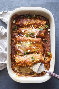 a casserole dish with meat, onions and parsley in it on a blue surface