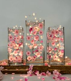 three glass vases with pink flowers and fairy lights