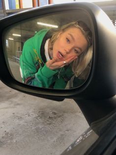 a woman looking at her reflection in the side view mirror