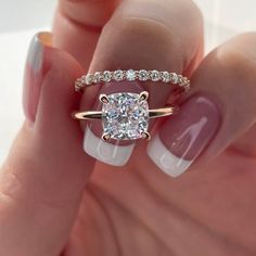 a woman's hand holding a ring with a diamond on it and a white manicure