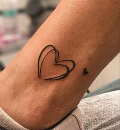 a small heart tattoo on the ankle, with hearts drawn in black and white ink