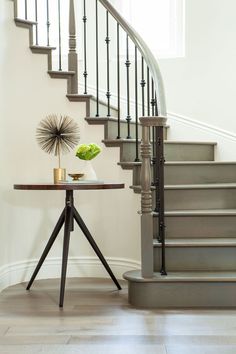 a table with a vase on top of it next to a stair case