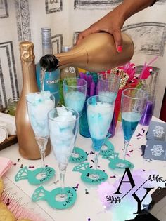 a table topped with lots of glasses filled with liquid and confetti next to bottles