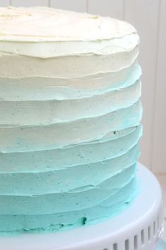 a blue and white frosted cake sitting on top of a counter next to a plate