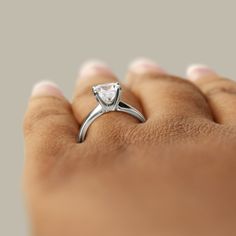 a woman's hand with a diamond ring on her finger, showing the center stone