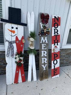 three wooden snowmen are standing next to each other with wreaths on their heads