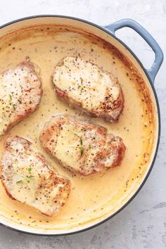 four pieces of meat are in a pan with gravy