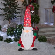 an inflatable santa clause is sitting on the snow covered ground next to christmas trees