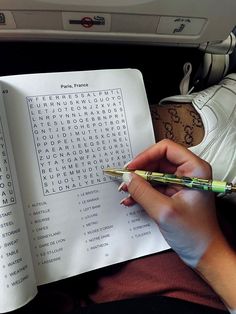 a person is holding a pen and looking at a crossword puzzle on an airplane