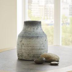 a gray vase sitting on top of a table next to two rocks and a rock