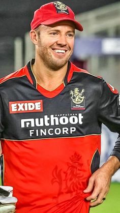 a man wearing a red hat and black shirt is standing in front of a green field