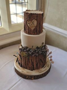 a three tiered wedding cake decorated with wood and flowers