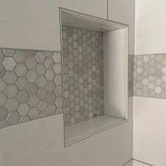 a white tiled bathroom with hexagonal tiles on the wall and shower stall door