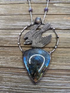 A richly detailed falcon swopping from the sky above a blue flash labradorite created with silver gleam solder (lead free). Adjustable chain with crystal bead accents. Labradorite is connected to strengthening psychic abilities and to the third eye chakra. Its ability to balance chakras make it an exceptional tool for promoting overall well-being and spiritual growth. One of the most prominent labradorite healing properties is its ability to protect against negative energies. Labradorite is also though to attracts luck and wealth. Celestial Silver Labradorite Jewelry, Celestial Silver Labradorite Necklace, Unique Silver Labradorite Necklace, Artisan Labradorite Necklace With Large Pendant, Silver Jewelry With Large Labradorite Pendant, Artisan Labradorite Jewelry With Large Pendant, One-of-a-kind Labradorite Round Pendant Jewelry, Soldered Labradorite Jewelry For Jewelry Making, Silver Labradorite Hand Forged Necklace