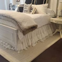 a white bed sitting in a bedroom on top of a hard wood floor