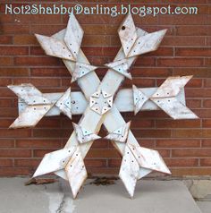 a metal snowflake sitting on top of a sidewalk next to a brick wall