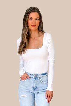 a woman in white shirt and jeans posing for the camera with her hands on her hips