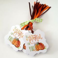 two tags that say happy thanksgiving and have pumpkins attached to them with ribbon on white background