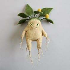 a stuffed toy with green leaves on it's head and roots attached to the body