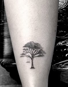 a small tree tattoo on the left leg is shown in this black and white photo