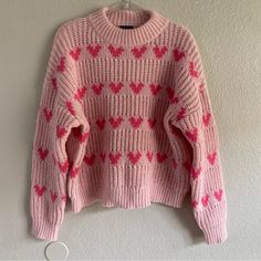 a pink sweater with hearts is hanging on the wall